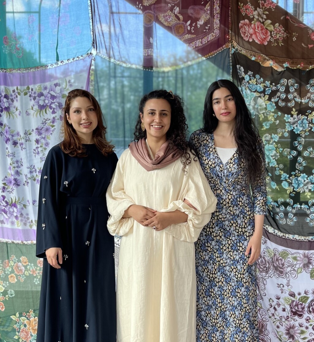 Drei Frauen stehen vor hängenden Tüchern