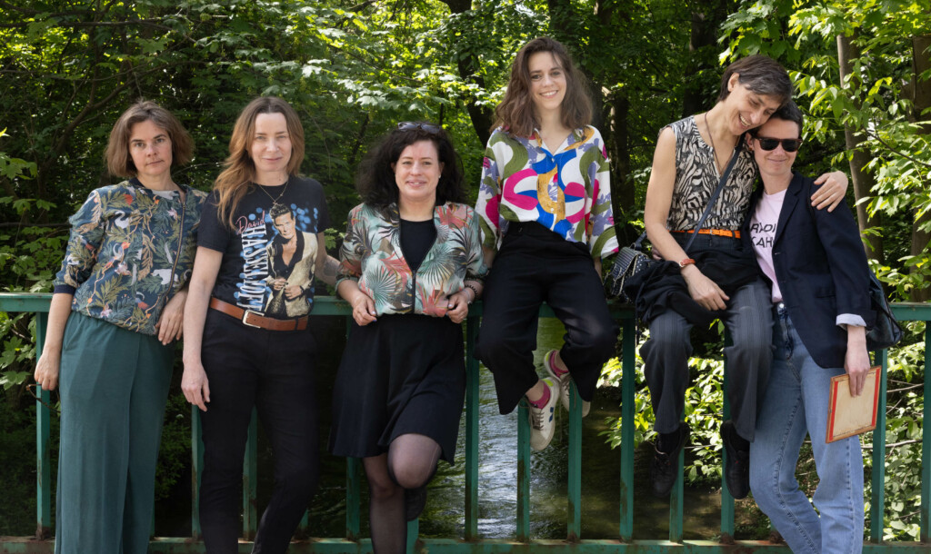 Sechs Frauen posieren auf einer Brücke über einen kleinen Fluss