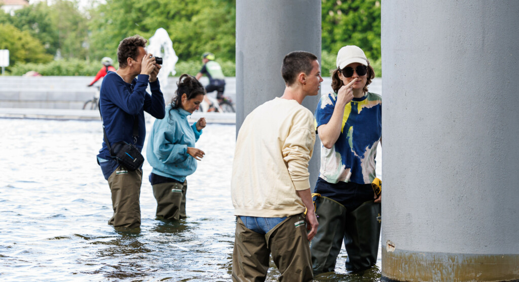 Menschen stehen in einem Wasserbecken und riechen an Säulen